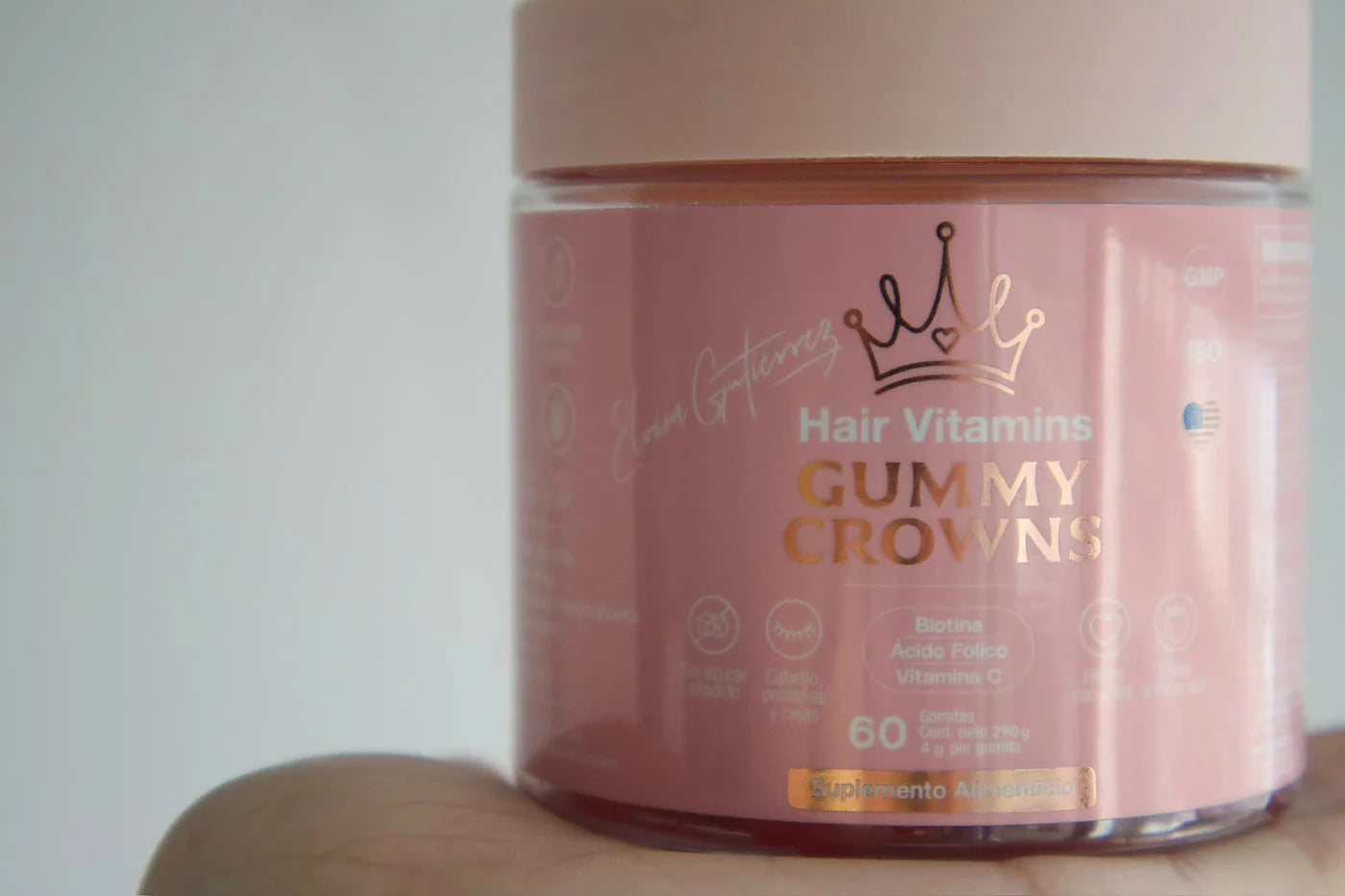 El bote de Gummy Crowns sostenido en la mano